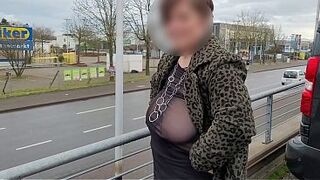 A gorgeous mature milf with a sheer top exposed her big tits in the street.